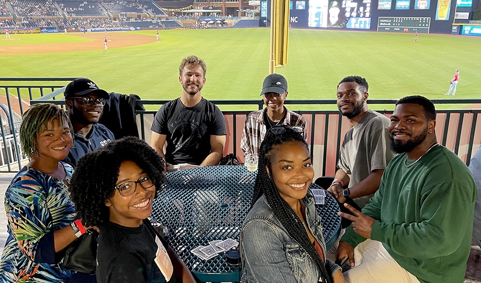 Group of people sit together at a baseball game.