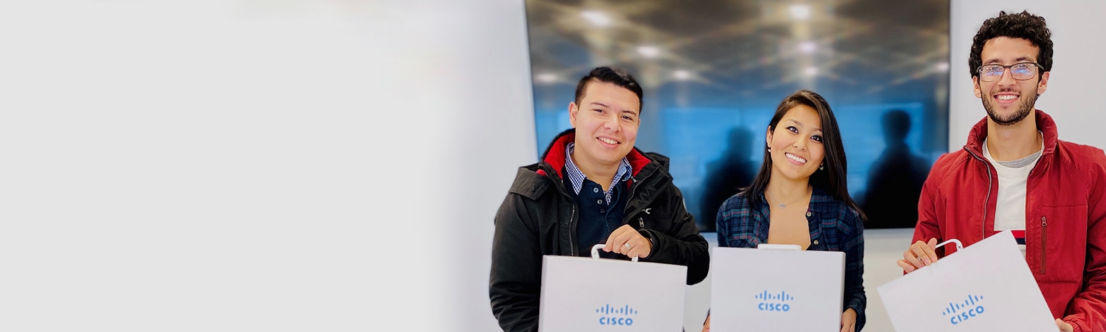 Three people stand together and smile while holding Cisco briefcases.