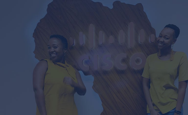 Two females wearing yellow in front of a brown wooden sign shaped like Africa with the Cisco Logo