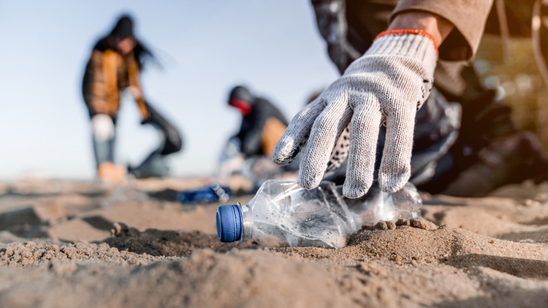 Aufsammeln von Plastikflaschen am Strand