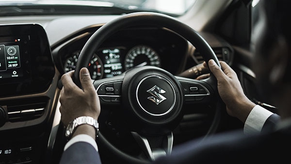 Person's hands on steering wheel with Suzuki logo