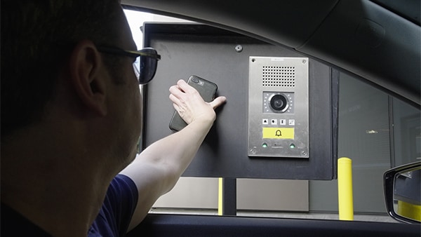 A driver in a car holds phone to scan parking reservation