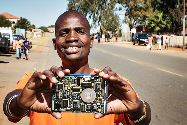 Smiling person standing on street and holding up a small motherboard