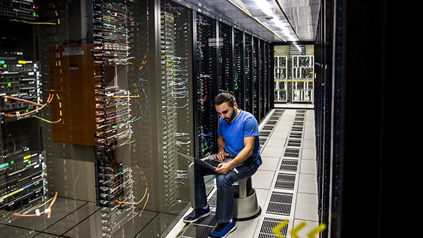 Man using laptop in a server room 