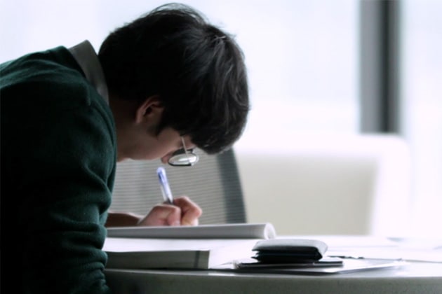 A glasses wearing student is studying 