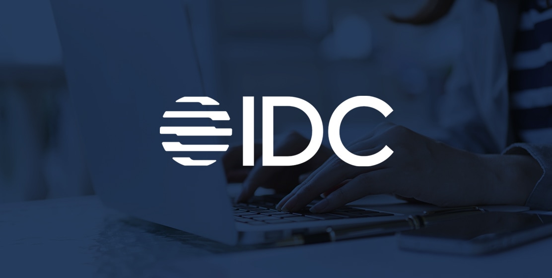 Logo der International Data Corporation (IDC) vor dem Bild eines Laptops
