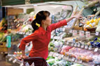 (photo: woman in store reaching for product)