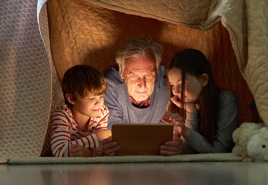 Children and their grandparent with a tablet computer or e-book.