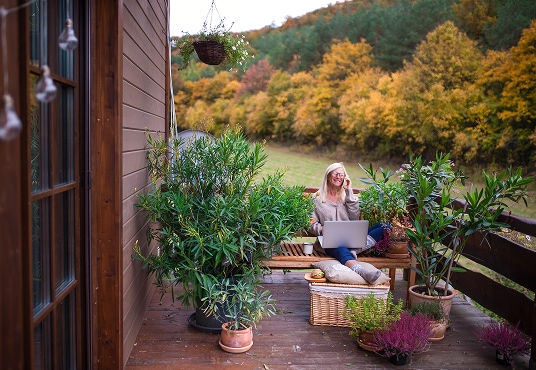 Senior with laptop and smartphone working outdoors on a terrace at home.