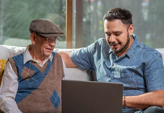 Adult senior father with his adult son, using a laptop together.