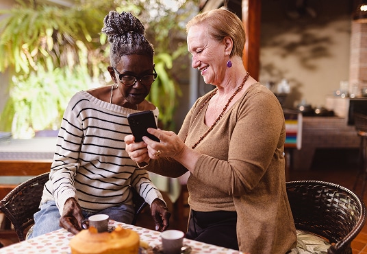 Senior showing photo on their smartphone to their friend.