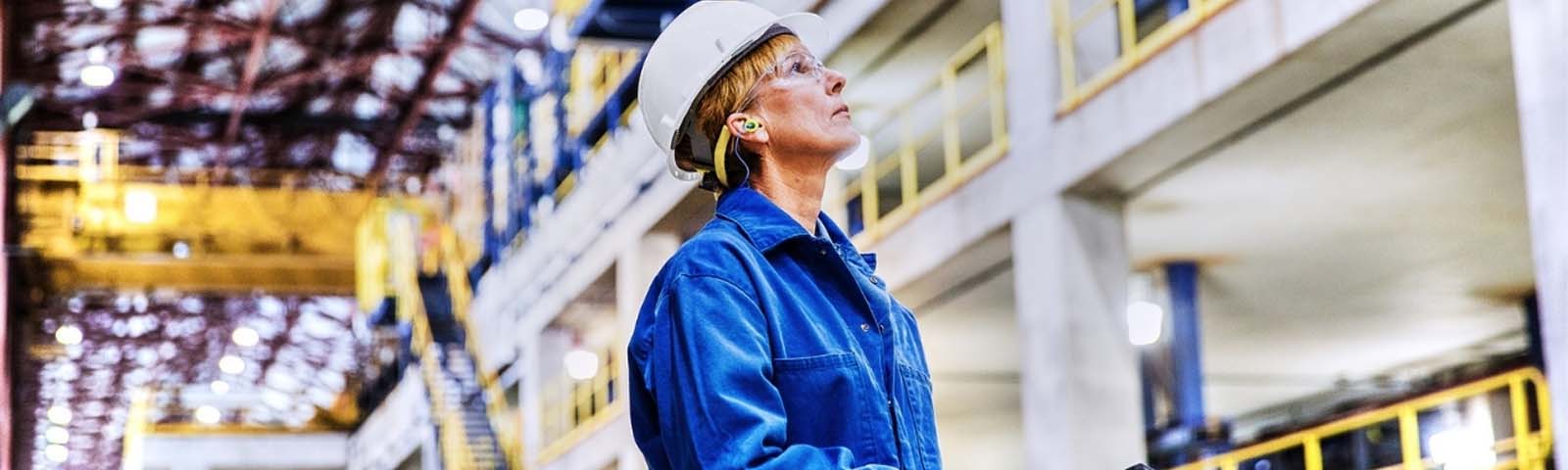 Een fabrieksmedewerker kijkt omhoog naar de fabriek