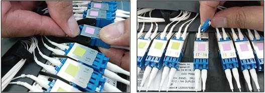A close-up of a finger holding a blue and white connectorDescription automatically generated
