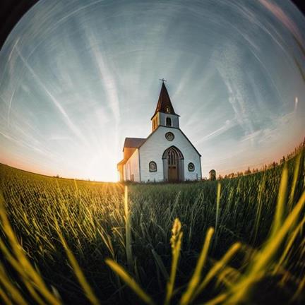 A white building with a steeple in a field of grassDescription automatically generated