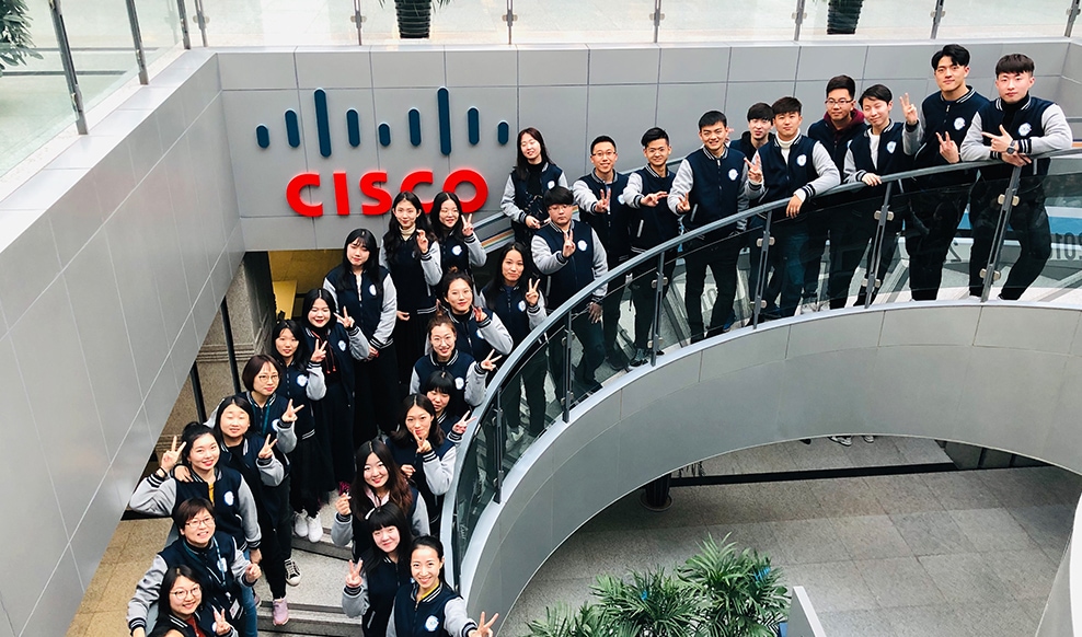 Large group of people stand on curved staircase with Cisco logo in the foreground.