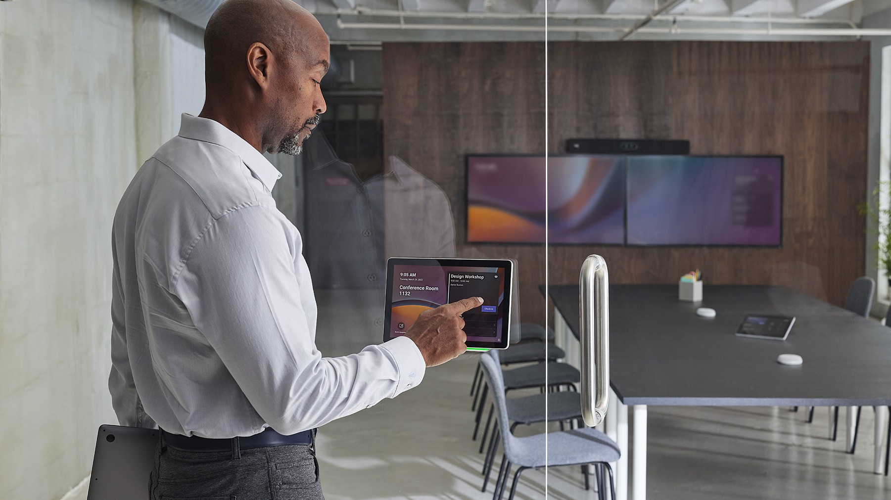 Cisco Room Navigator mounted on glass wall, running the native Microsoft Teams panel application