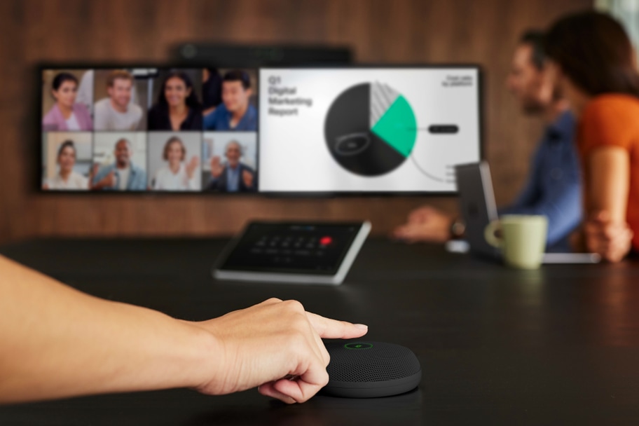 The carbon black Cisco Table Microphone Pro on a meeting room table connected to the Room Bar Pro.