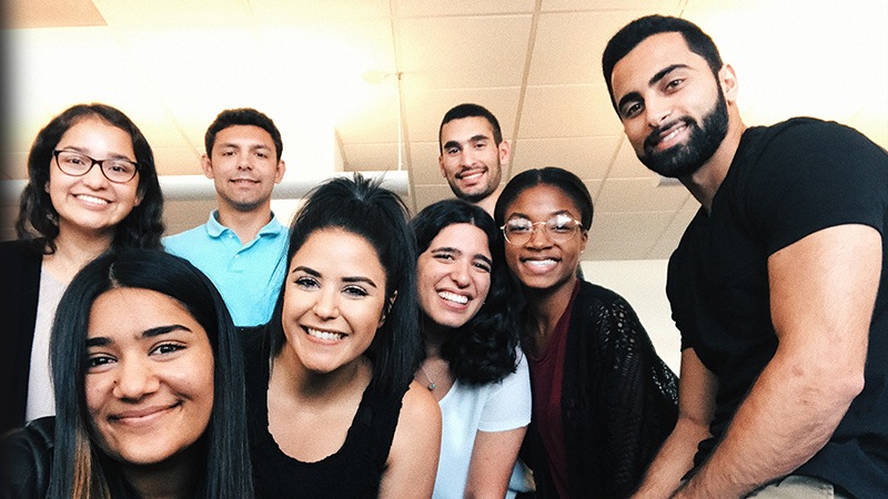 Eight people huddled together and smiling.