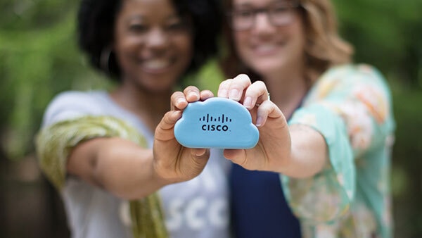 Two females holding a stress toy shaped like a cloud with Cisco logo on it.