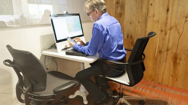 Man sits at desk with computer and cell phone