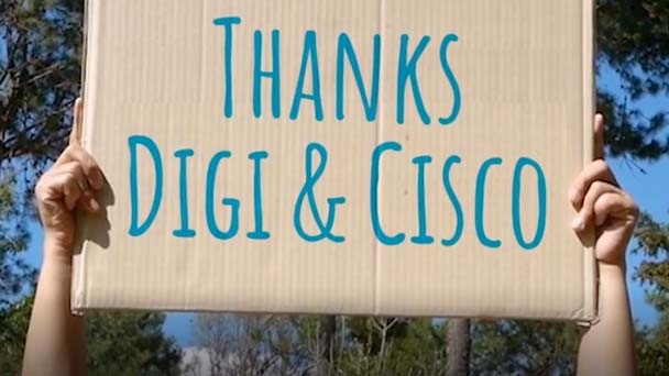 Person holds a hand-lettered sign that says “Thanks DiGi and Cisco”