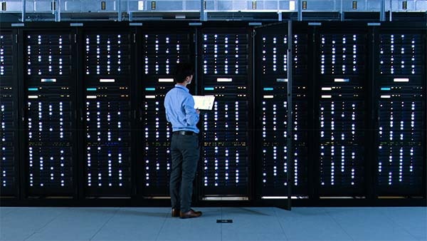 A man stands in front of server racks