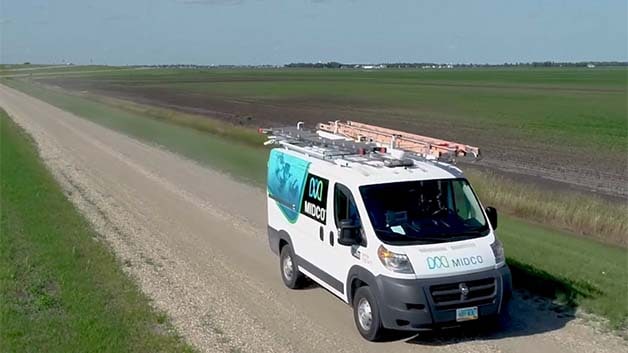 A Midco van travels a rural road
