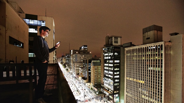 Person on building rooftop looks at mobile device