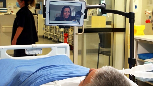 A woman is shown on a screen during a virtual visit in the hospital ICU