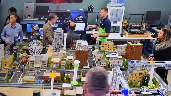 People at trade show standing around a table on which model city infrastructure is displayed