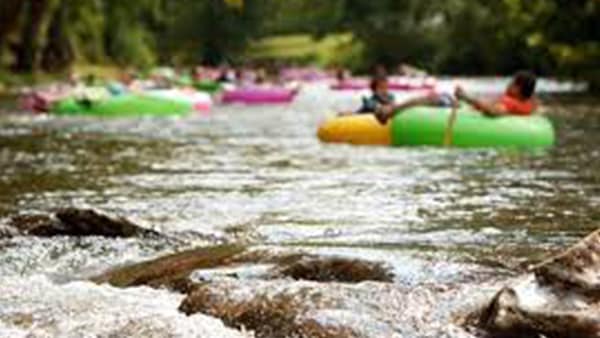 Multiple people floating down river in neon-colored inner tubes