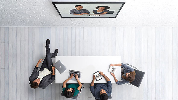 Top view of a conference room with four people working on their laptops and tablets. 