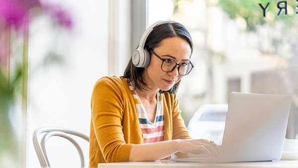 A woman wearing headphones reading on her laptop