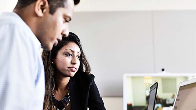 Two people in an office, looking at a computer screen together