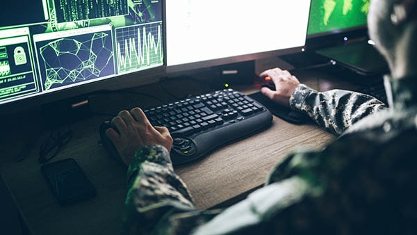 Man in military fatigues using computer