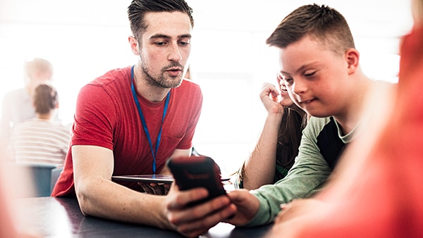 A teacher helps a young student develop digital skills.