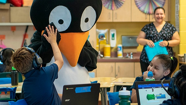 Student high-fives with MIND’s penguin mascot