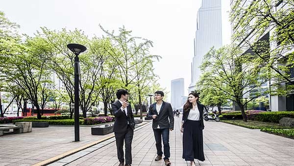 Three businesspeople talking and walking on a sidewalk 
