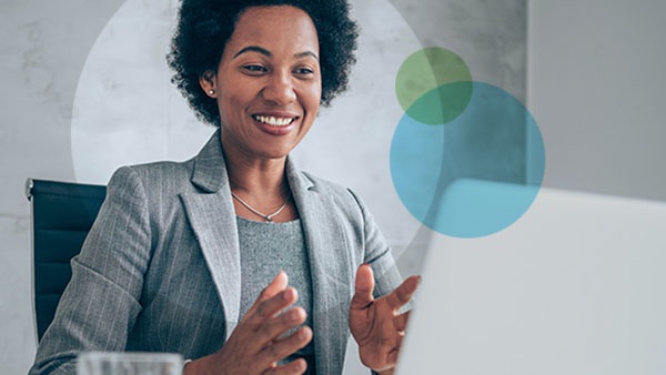 A happy female employee in a call on her laptop smiling with her hands mid-gesture.