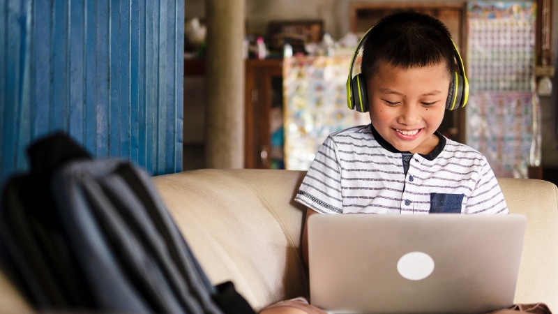 Child working on a laptop with headphones on.