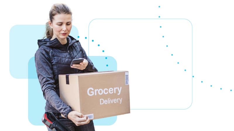 Person holding a mobile device and a grocery delivery box