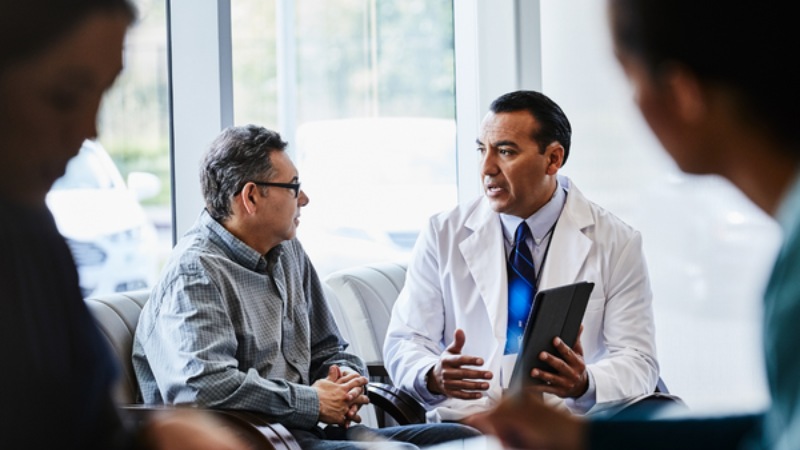 Doctor talking to patient while holding a tablet