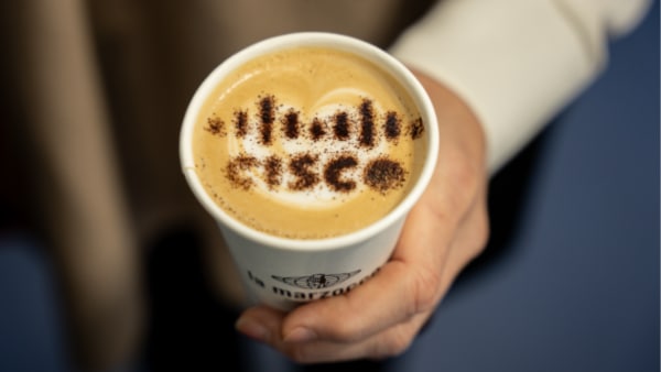 Person holding coffee with Cisco logo