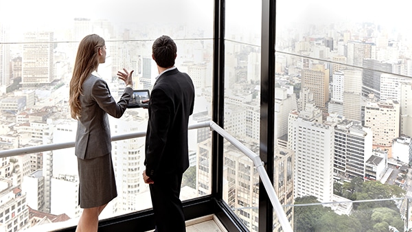 Two business people in a building looking out at a city