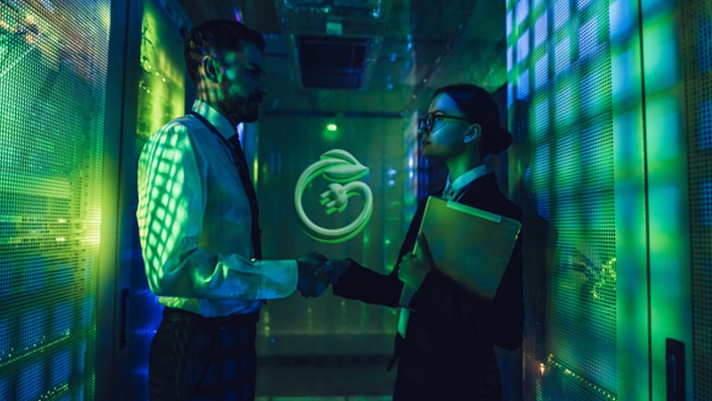 Two people shaking hands in a data center with green lighting. An icon representing energy efficiency is visible above their hands.