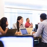 Four employees working on their laptops in open area at the office 
