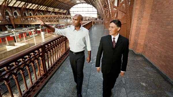 Deux personnes marchant sur la mezzanine d’une gare.
