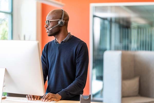 Man standing at desk with headset