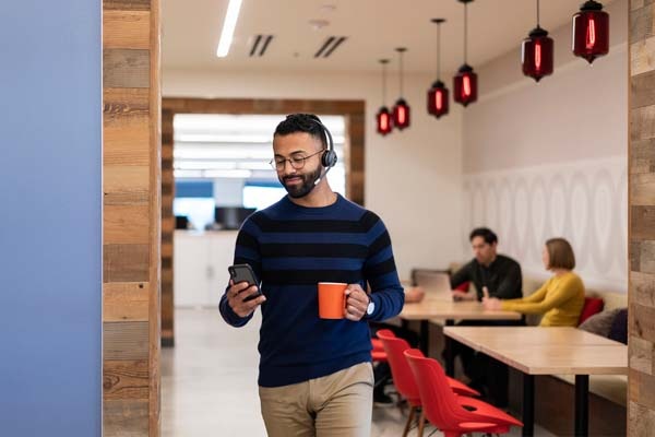 Man walking with coffee wearing headset