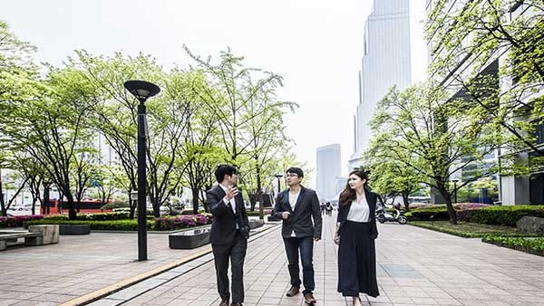 세 명의 비즈니스 종사자들이 보도에서 이야기하며 걷고 있는 모습